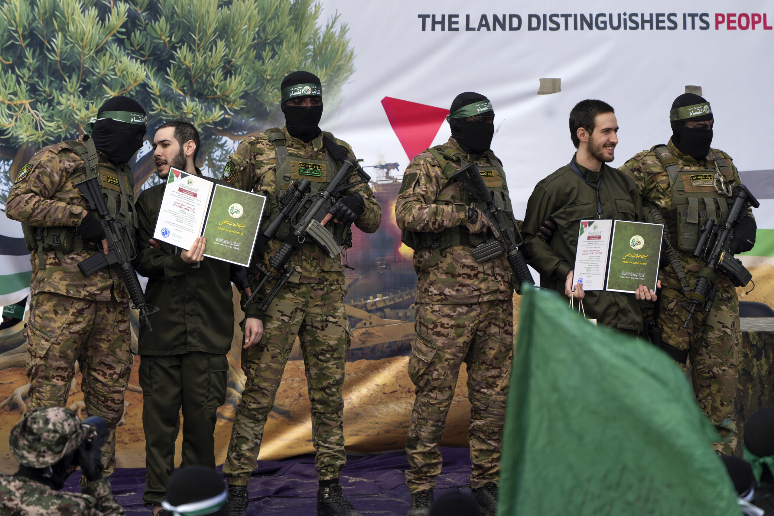 middle east one of the 3 hostages on stage kisses a hamas militiaman on the head scaled